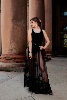 Young woman in sexy transparent black dress near the ancient building. Vintage building. Fashion woman. Young woman modern portrait.