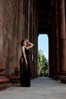 Young woman in sexy transparent black dress near the ancient building. Vintage building. Fashion woman. Young woman modern portrait.