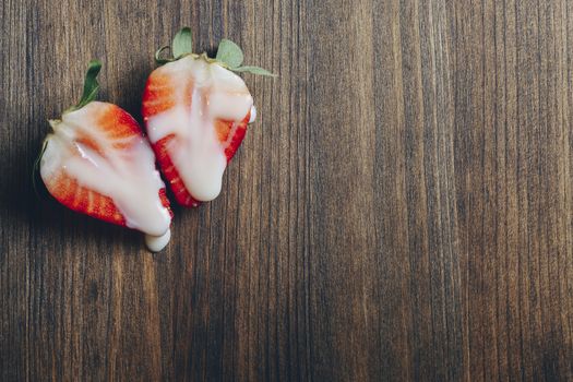 metaphor of sex with strawberries and milk on a wooden table, top view, copy space for text