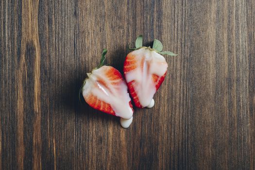 metaphor of sex with strawberries and milk on wooden background, top view, copy space for text
