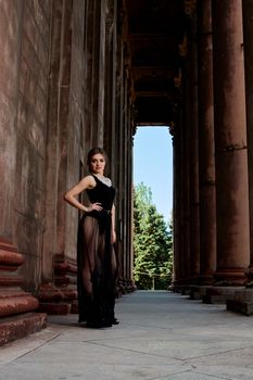 Young woman in sexy transparent black dress near the ancient building. Vintage building. Fashion woman. Young woman modern portrait.