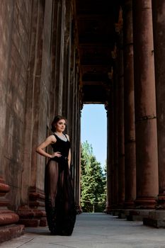 Young woman in sexy transparent black dress near the ancient building. Vintage building. Fashion woman. Young woman modern portrait.