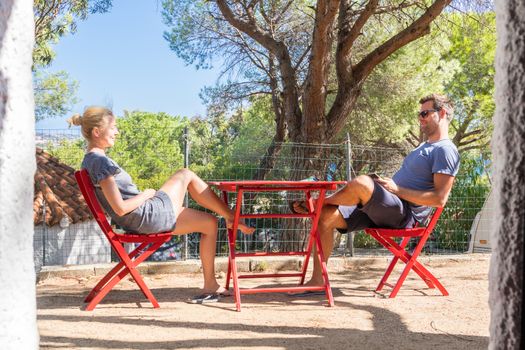 Couple on vacations resting and enjoing in front of mobile home house at camping site in pure nature. Family vacation travel, holiday trip Sardigna, Italy.