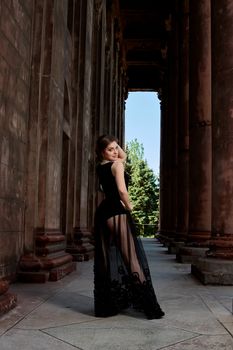 Young woman in sexy transparent black dress near the ancient building. Vintage building. Fashion woman. Young woman modern portrait.