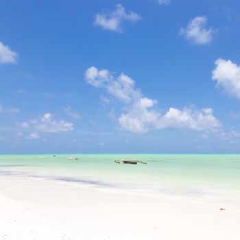 Solitary fishing boat on picture perfect white sandy beach with turquoise blue sea, Paje, Zanzibar, Tanzania. Copy space.