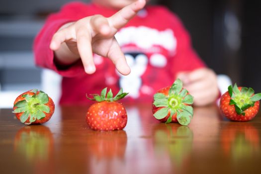 Baby exploring some fruits with his hand on a dark wooden table
