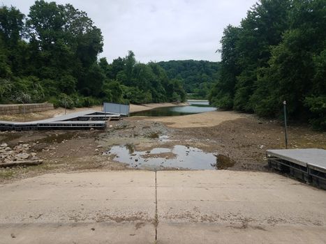 trees with dry lake or pond with boat ramp and piers