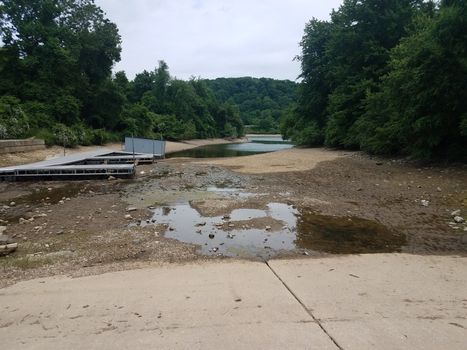 trees with dry lake or pond with boat ramp and piers