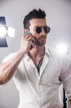 Attractive VIP man in studio with spotlights behind him, talking on cellphone