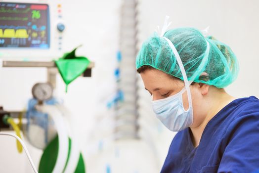 Veterinarian doctor portrait in operating room. Anesthesia monitoring in the background