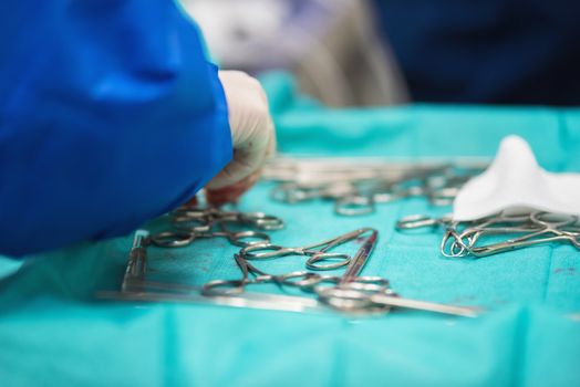 Surgeon hand picking up an instrument from tray of surgical instruments