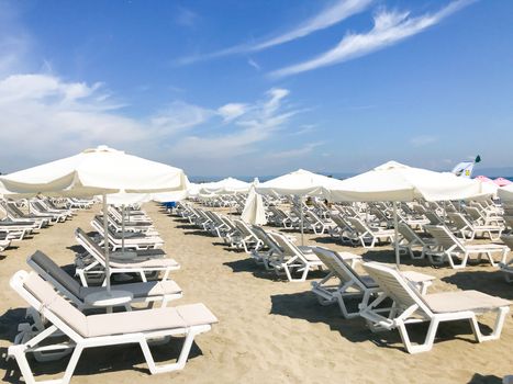 White Loungers And Umbrellas At The Beach In Pomorie, Bulgaria.