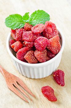 Dried Strawberries in white cup on wooden background.