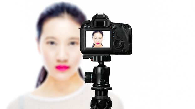 Focus on live view on camera on tripod, teenage girl  beauty shoot image on back screen with blurred scene in background. Teenage vlogger livestreaming show concept