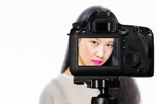 Focus on live view on camera on tripod, teenage girl  makeup beauty shoot image on back screen with blurred scene in background. Teenage vlogger livestreaming show concept