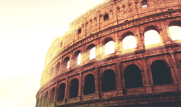 dramatic image of the Colosseum of Rome during sunset with sun rays filtering through the arches