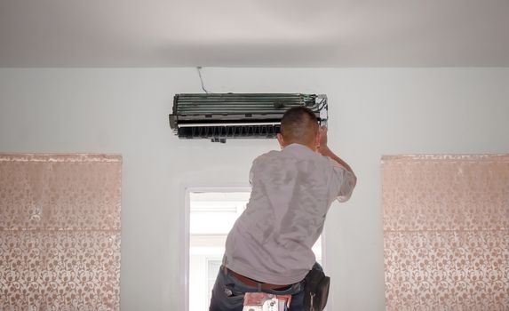 Air Conditioning Repair Man Works on an AC Unit in a Residence
