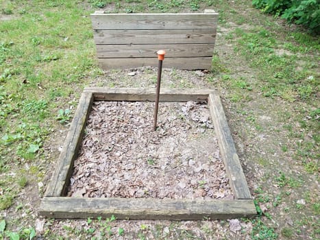 dirt horseshoe pit with metal pole and wood backstop