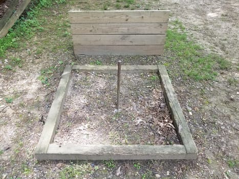 dirt horseshoe pit with metal pole and wood backstop