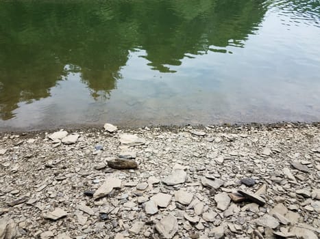 broken grey rocks and water at shore of river or lake or pond