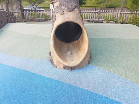 tree log slide on playground with soft blue and green surface or ground