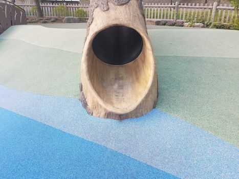 tree log slide on playground with soft blue and green surface or ground