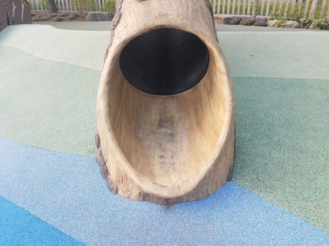 tree log slide on playground with soft blue and green surface or ground