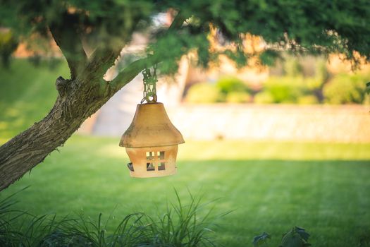 Clay or ceramic bird feeder hanging on a tree, soft blurry background