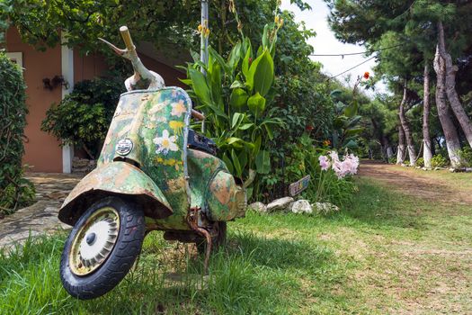 An old abandoned painted motorcycle in a garden at Corfu island, Greece.