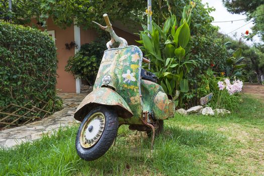 An old abandoned painted motorcycle in a garden at Corfu island, Greece.