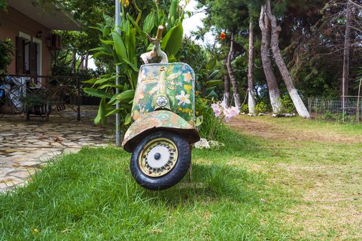 An old abandoned painted motorcycle in a garden at Corfu island, Greece.