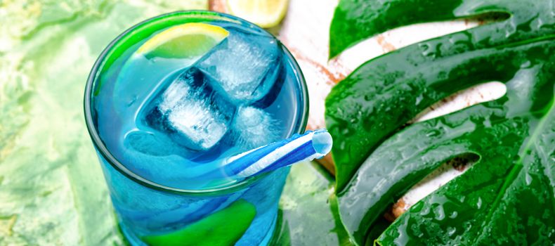 Glasses with blue alcoholic cocktail with ice and lime