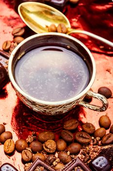 Hot coffee and sweets.Coffee cup, beans,chocolate on kitchen table.Mix of chocolate sweets