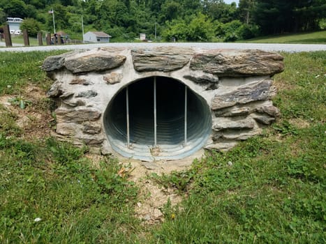 metal drain or tube or tunnel with bars and green grass