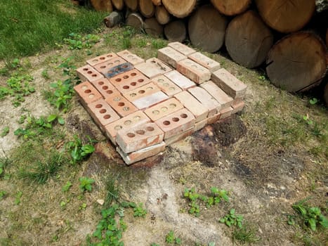 tree stump with red bricks or masonry and stacked firewood