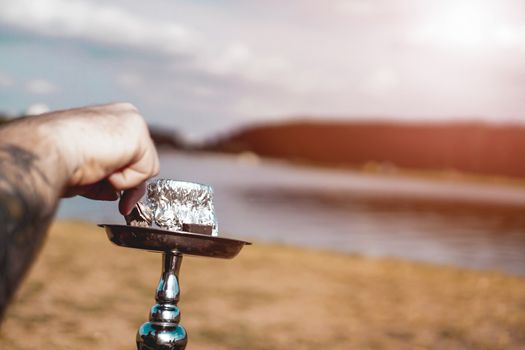 Summer vacation, activity. environment, travel and hookah smoking concept. Hookah bowl stands in nature by the river close up