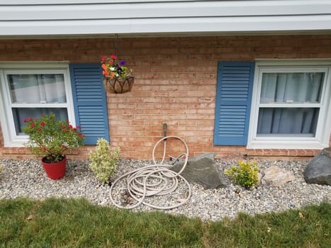 red bricks, blue shutters, garden hose and stones and rocks