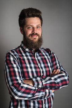 Smiling bearded man in checked shirt, portrait, studio shot on gray background