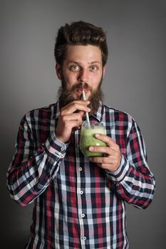 Young Man looks wondering tasting drinking delicious green spinach smoothie