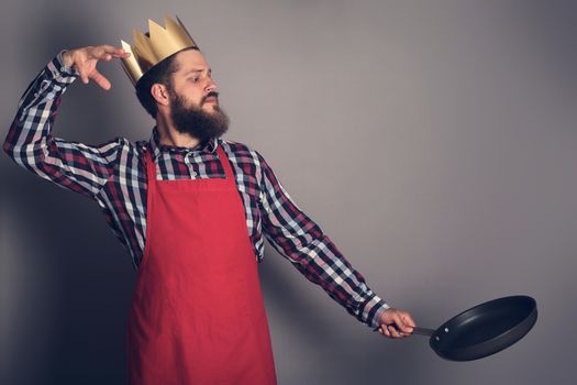 Cooking man concept, king of kitchen,bearded man in checked shirt, drop up something from a pan, studio shot on gray background copy space for text