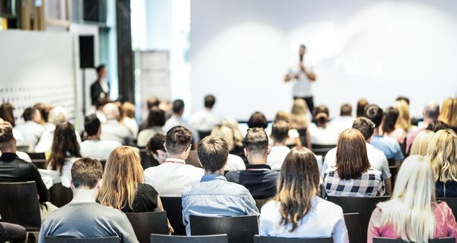 Audience at the conference hall. Male speaker giving a talk in conference hall at business event. Business and Entrepreneurship concept. Focus on unrecognizable people in audience.