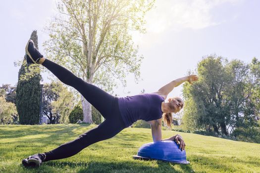healthy young woman planking on the grass on a sunny day, she is outdoors in a park at the morning