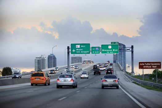 Miami, FL, USA - May 12, 2013: Evening traffic on highway, Miami, USA. Cars moving on a highway with directional signs to Miami International airport, Miami downtown and Miami Beach.