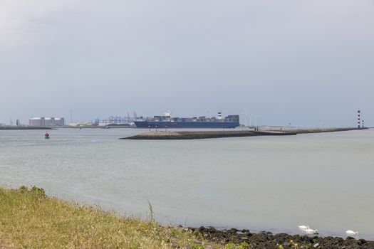 Container ship entering the harbour of the europoort maasvlakte near rotterdam in holland, the biggest harbour in holland