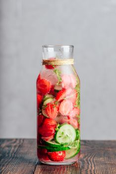 Bottle of Flavored Water with Fresh Strawberry, Sliced Cucumber and Springs of Thyme. Copy Space and Vertical Orientation.