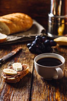 Breakfast with Banana Sandwich with Chocolate Spread, Cup of Coffee and Grapes.