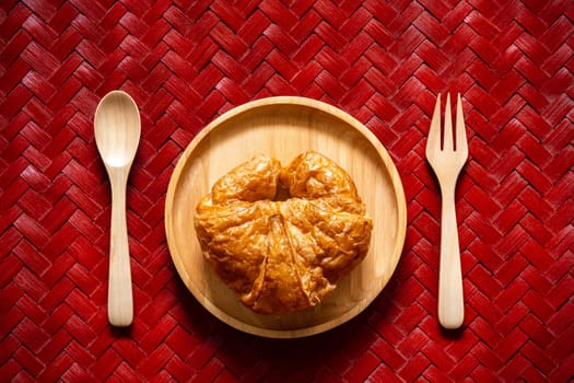 Top view croissants on wooden dish with spoon and fork on texture of woven bamboo.