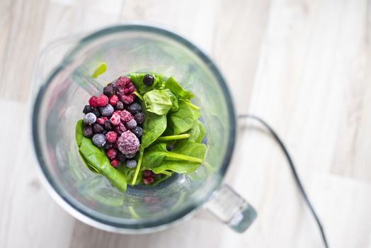 Frozen berries and spinach leaf ready for smoothie blending.