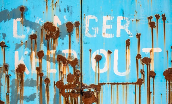 Grungy Rusty Danger Keep Out Sign Painted On To Some Heavy Industrial Doors
