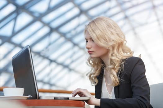 Young business woman wearing suit using laptop computer. Female working on laptop in cafe